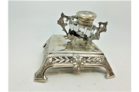 Tinteiro em prata vazado com suporte para canetas e assente sobre quatro pés.